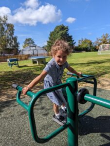 A young girl can be seen using one of the outdoor Gym apparatus on the academy grounds and smiling for the camera.