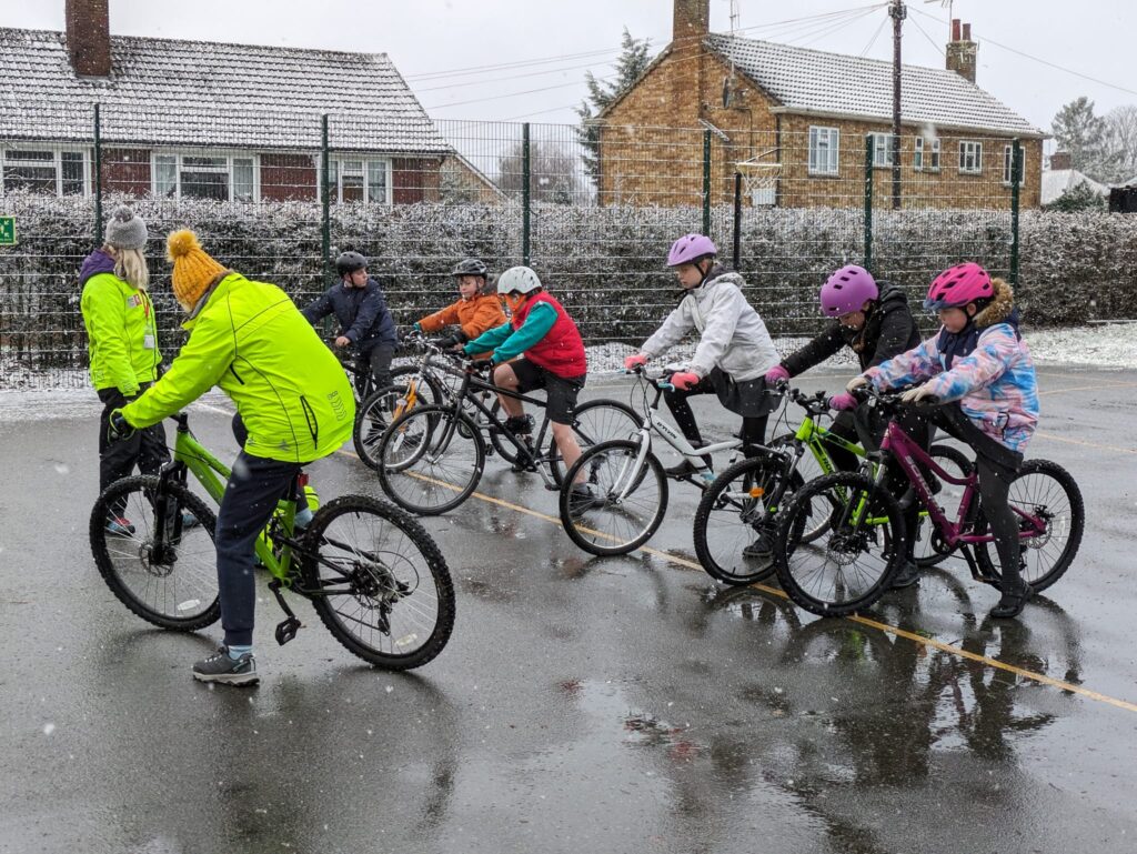 Year 6 pupils participating in Bikeability on the academy playground on a snowy winter's day.