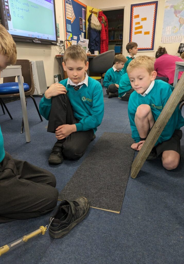 Year 6 pupils are seen experimenting with friction on different materials and surfaces.