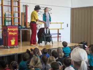 Photo taken of the Magic Show, organised by FoHPS, with a young female pupil seen participating in a trick with the magician.