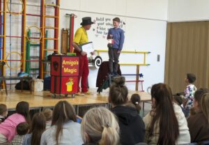 Photo taken of the Magic Show, organised by FoHPS, with a male pupil seen participating in a trick with the magician.