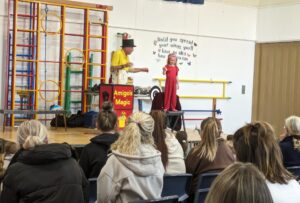 Photo taken of the Magic Show, organised by FoHPS, with a young female pupil seen participating in a trick with the magician.