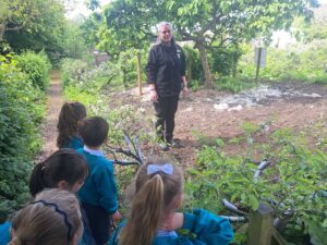 A group of Years 1 and 2 pupils are pictured gathered in front of a member of staff to listen to her, during a trip to Kent Life.