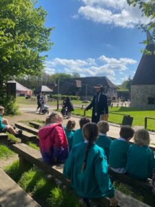 A group of young pupils from Years 1 and 2 are pictured gathered around a member of staff who is speaking to them, during a school trip to Kent Life.