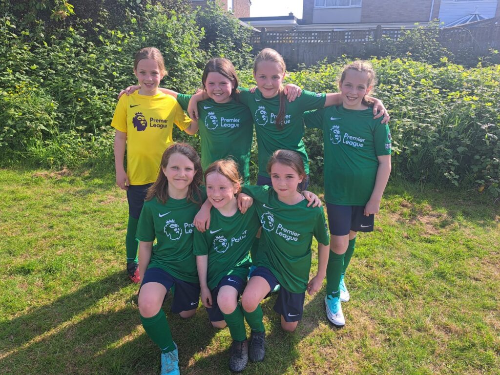 Photo showing the Year 5 Girls Football team at Horsmonden Primary Academy, posing together as a group, after having played a match.